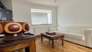 Amplia sala de estar con un sofá blanco, una mesa de centro de madera y un mueble de madera con puertas de cristal.