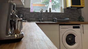 Una cocina moderna con lavadora integrada, microondas y ventana con vistas a un árbol.