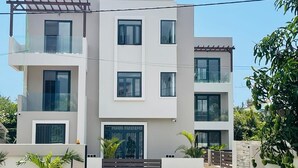 A modern multi-story residential building with a flat roof, large windows, and a balcony. - RABBIT HOLIDAY - 8 mins walk to the beach (Flic en Flac)