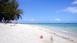 A beach with white sand, clear blue sky, and turquoise water. - RABBIT HOLIDAY - 8 mins walk to the beach (Flic en Flac)
