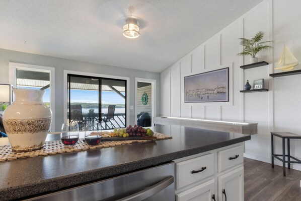 A modern kitchen with a large island, white cabinetry, and a view of the outdoors.