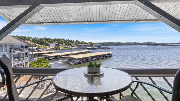 Un balcon avec une table et des chaises donnant sur une marina, où l’on peut admirer des bateaux et des quais.