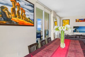 A dining area with a red tablecloth, white flowers, and a painting of a coastal scene. - *LUXURY KINGDAVID*3/2C*KINGBEDROOM*BEST LOCATION* (Sunny Isles Beach)