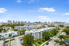 A modern apartment complex with multiple buildings, parking areas, and a clear view of the city skyline in the background. - *LUXURY KINGDAVID*3/2C*KINGBEDROOM*BEST LOCATION* (Sunny Isles Beach)