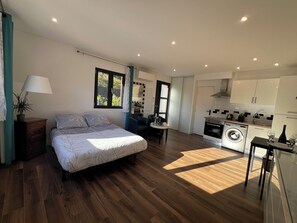 A bedroom with a bed, a bedside table with a lamp, and a window.