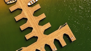An aerial view of a wooden pier extending into a body of water, with a small boat docked at one end. - Pousada & Restaurante Praeros LTDA (Rifaina)