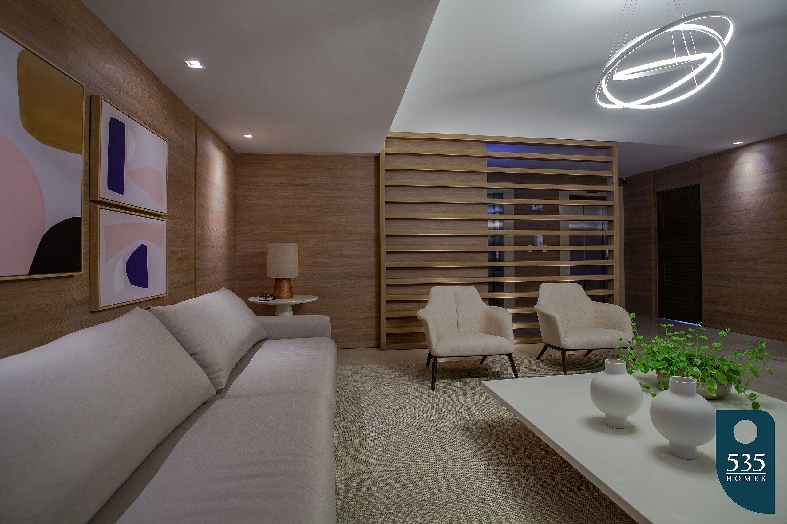 Un salon moderne comprenant un canapé, deux fauteuils, une table basse et une plante décorative.
