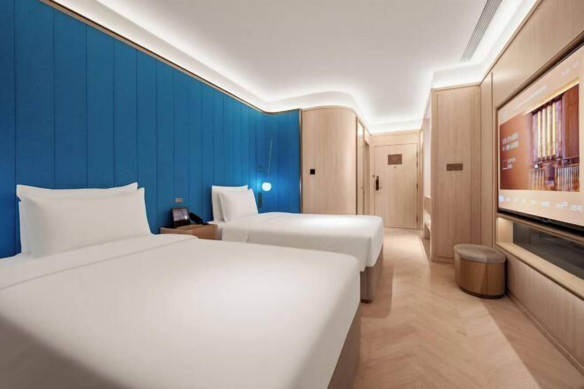 Ein Hotelzimmer mit zwei Betten, einem Fernseher und einem Holzschrank.