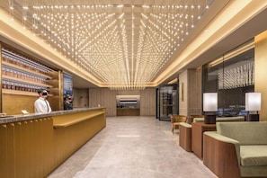 Eine Hotelhalle mit einer Rezeption, einer Sitzecke und einer Kristallleuchter.