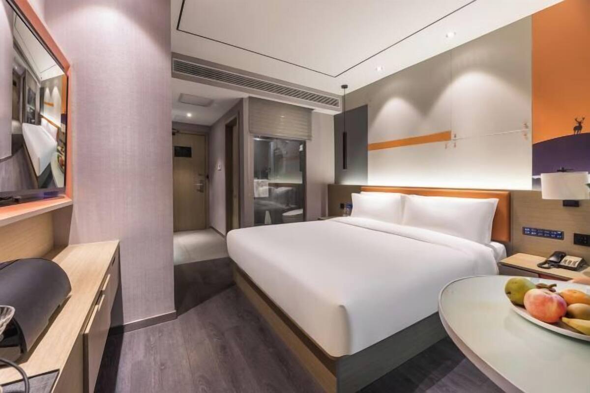 Ein Hotelzimmer mit Bett, Schreibtisch und einem kleinen Tisch mit Obst.