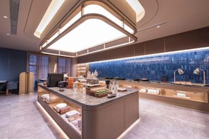 Eine moderne Hotelhalle mit einer zentralen Insellounge, einer blauen Wandfliese und einer Rezeption.