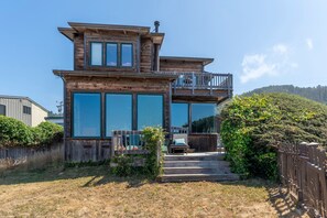 Una casa de madera de dos pisos con ventanas grandes y un balcón.