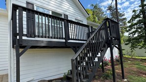 Une maison dotée d’une terrasse en bois et d’un escalier menant à un porche abrité.
