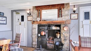 A rustic interior with a stone fireplace, wooden furniture, and a vintage stove. - Captains Cove at The Fishing Boat inn (Boulmer)