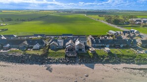 A coastal village with traditional stone houses, a sandy beach, and a green field in the background. - Captains Cove at The Fishing Boat inn (Boulmer)