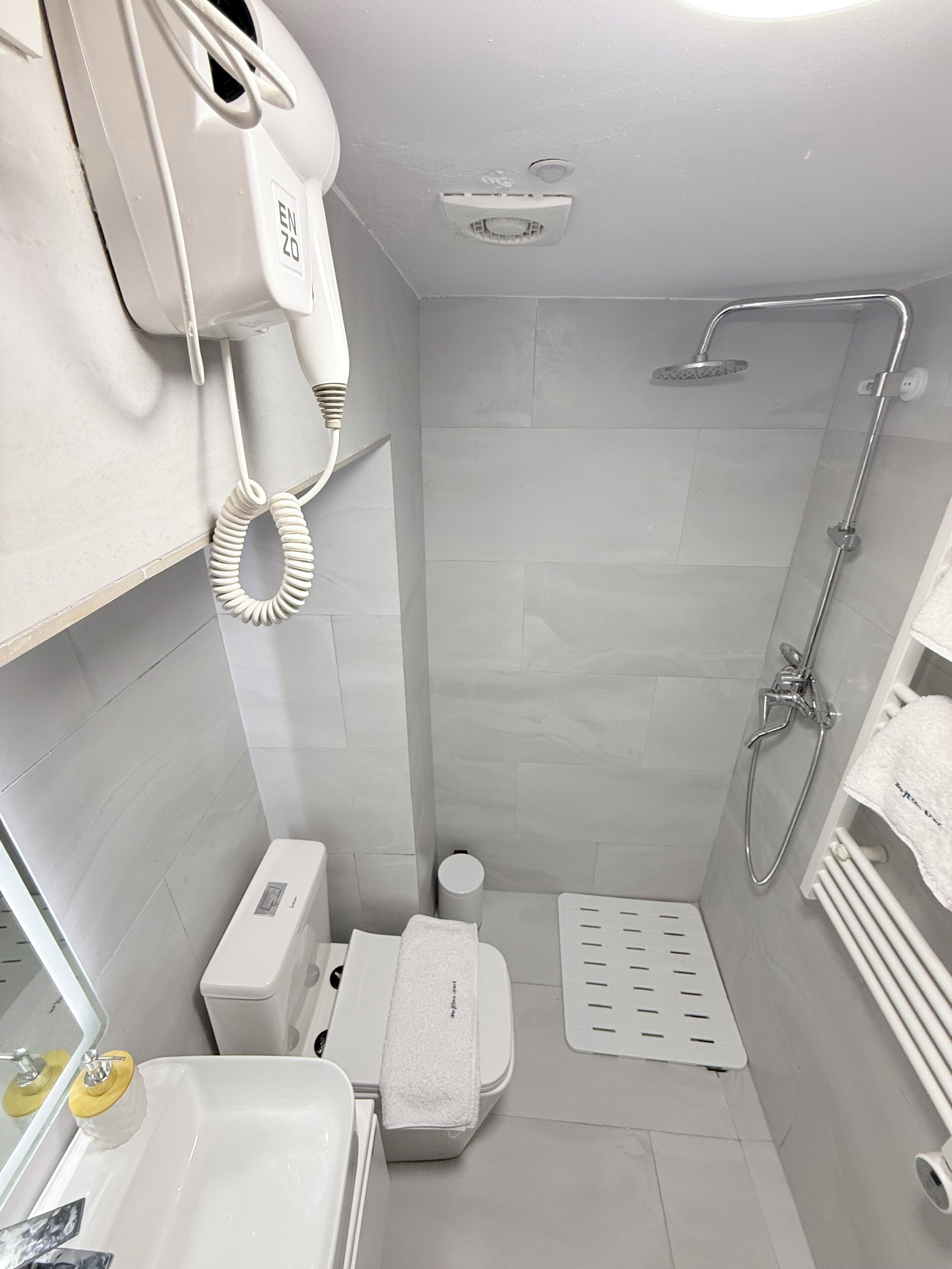 A small, modern bathroom with a toilet, sink, and shower.