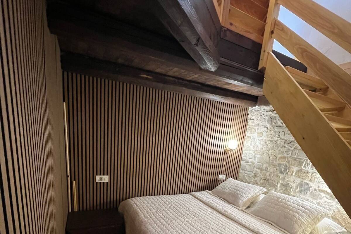Een gezellige slaapkamer met een houten stapelbed, een stenen muur en een schuine plafond.