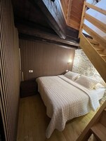Um quarto aconchegante com uma cama de madeira beliche, parede de pedra e teto inclinado.