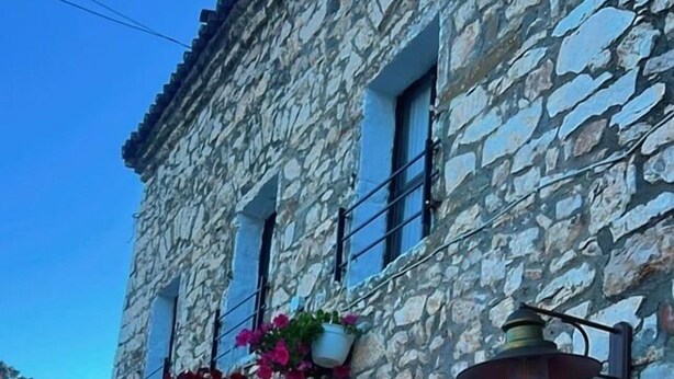 Un bâtiment en pierre doté de nombreuses fenêtres, dont certaines sont ornées de jardinières, et une rangée de panneaux d’information placés au niveau du sol.