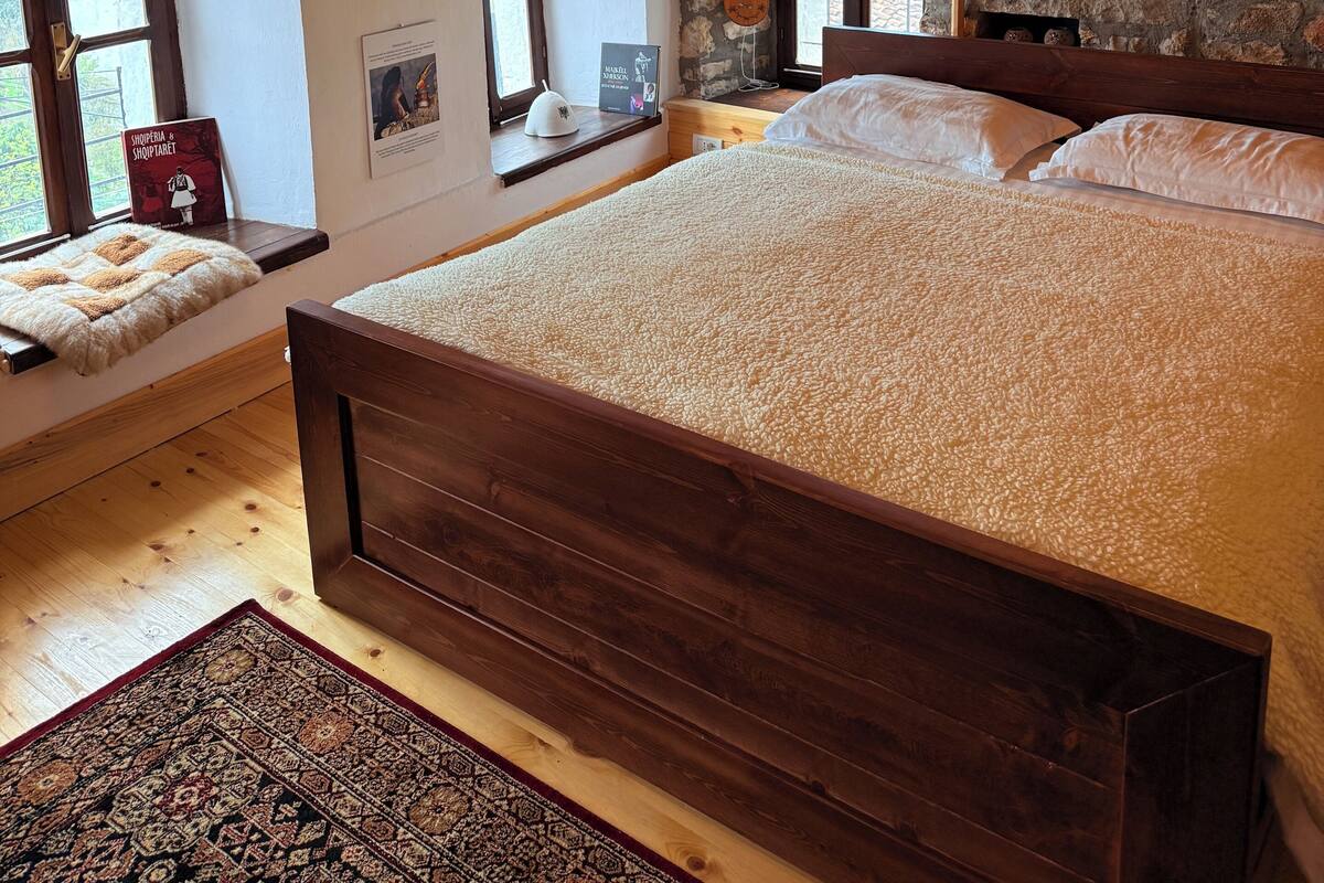 Een slaapkamer met een houten bed, stenen muren en boogvensters.