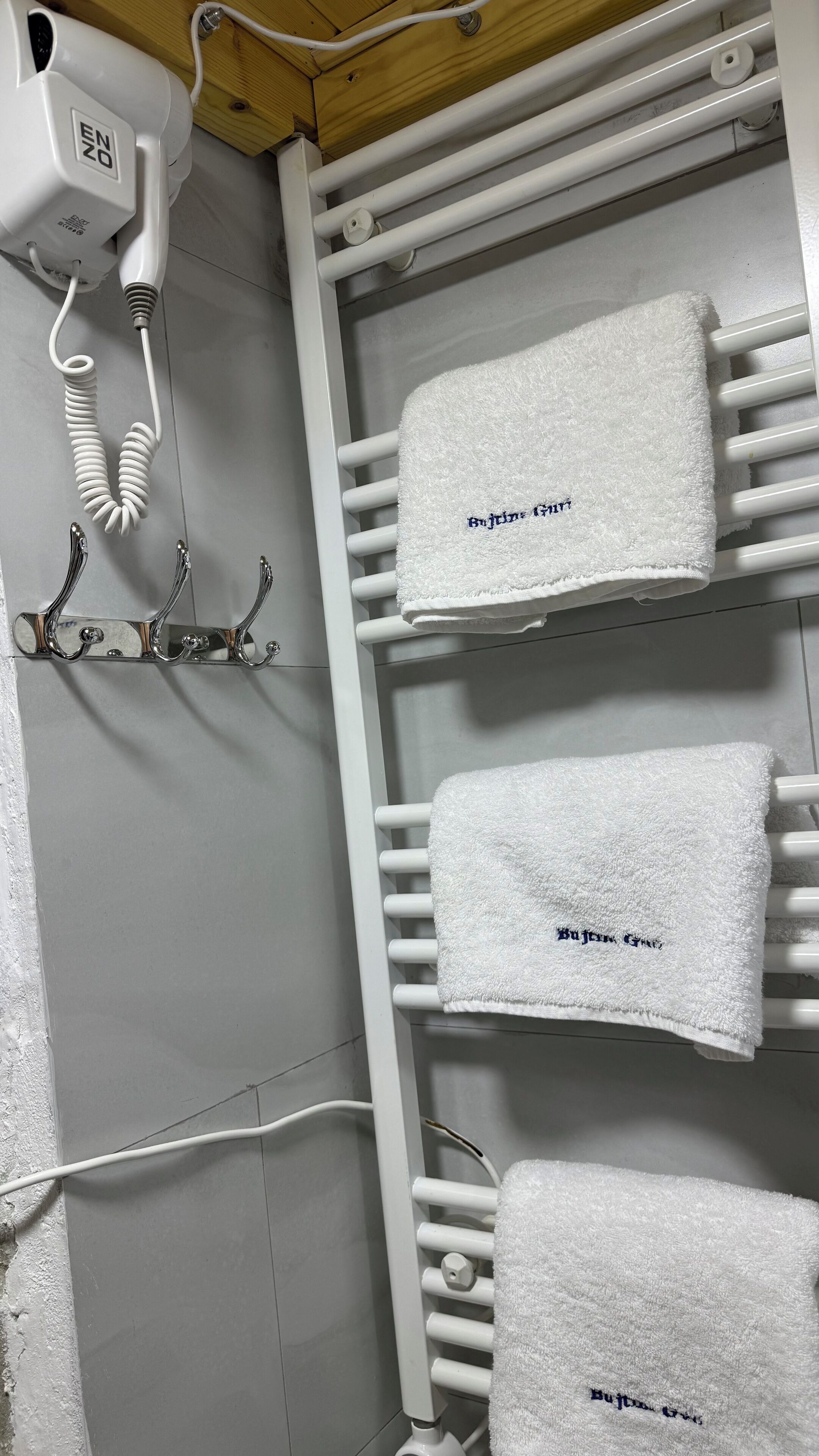 Un baño con un toallero blanco que sostiene tres toallas, cada una con un nombre bordado.