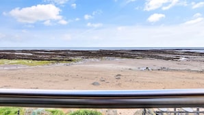 Ein Küstenstrand mit Felsformationen und blauem Himmel.