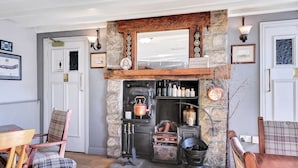 Ein rustikales Interieur mit Kamin aus Stein, Holzmöbeln und einem alten Herd.