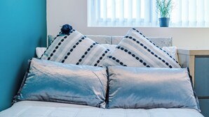 A bed with a white quilted cover and two pillows with a striped pattern. - 3 Bed-sleeps 5-garden-parking (Liverpool)
