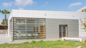 Un edificio moderno con un amplio ventanal, una puerta y un banco en la entrada.