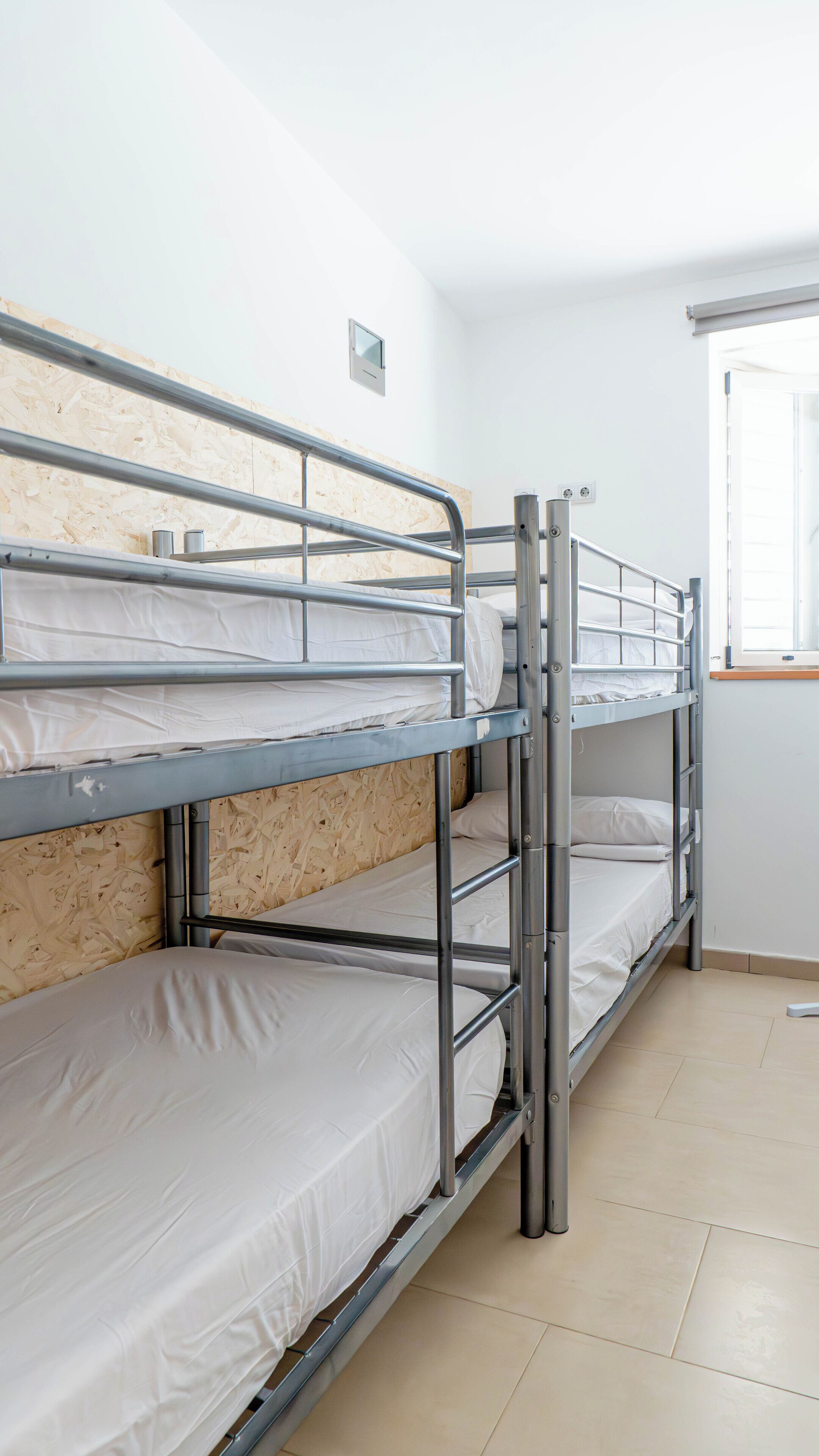 Ein Schlafzimmer mit Etagenbetten, Metallgeländern und weißer Bettwäsche.