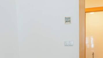 A single-bed room with a wooden door leading to a bathroom.