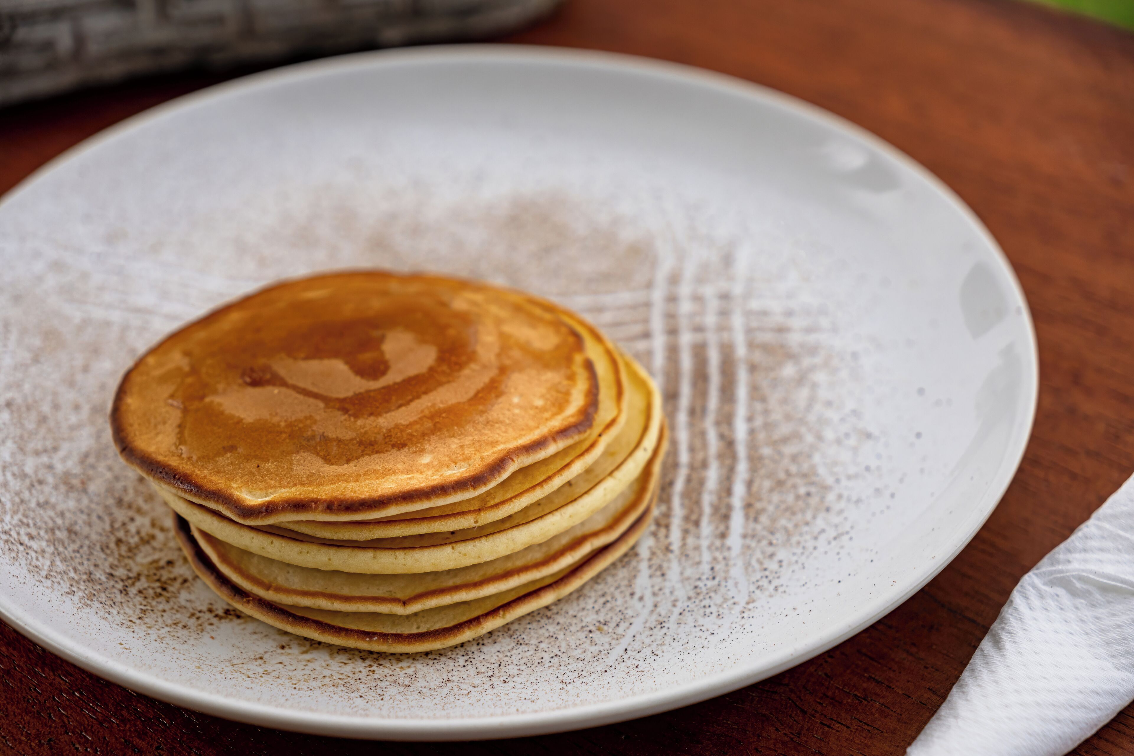 Une pile de crêpes sur une assiette blanche à surface texturée.