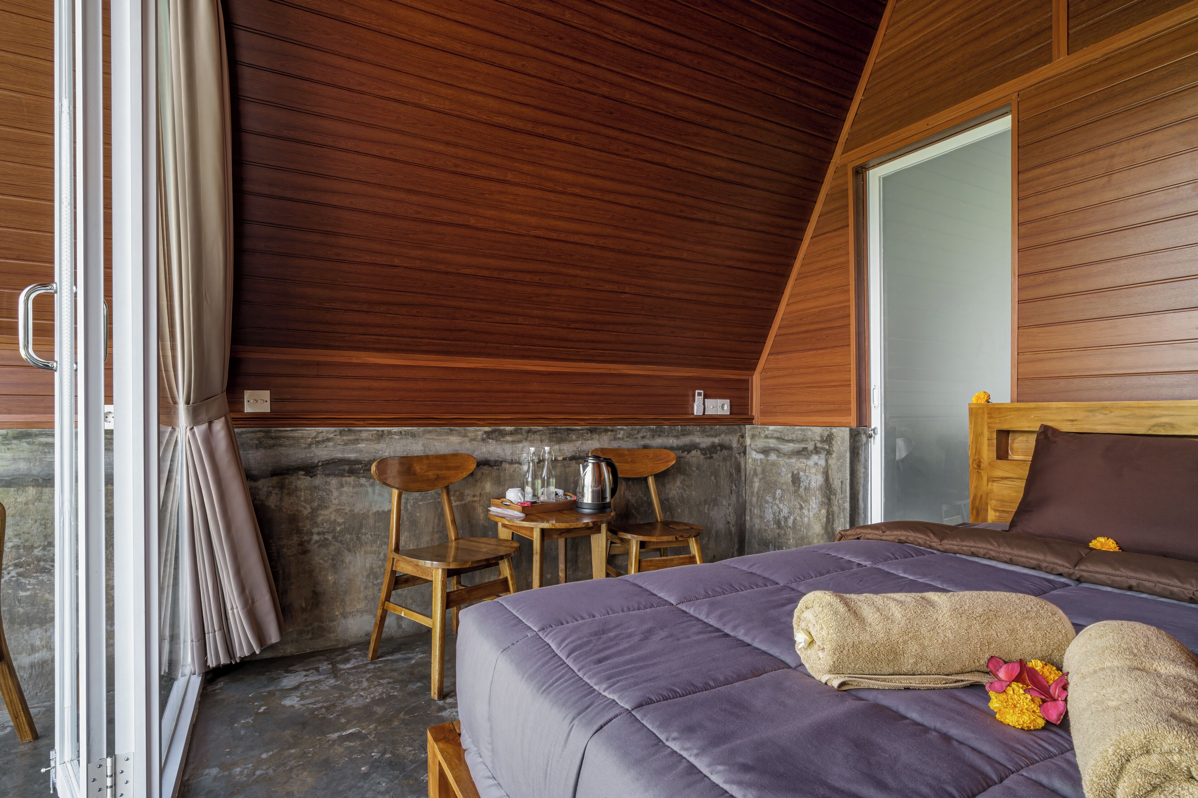 A room with a bed, wooden ceiling, and a table with chairs.