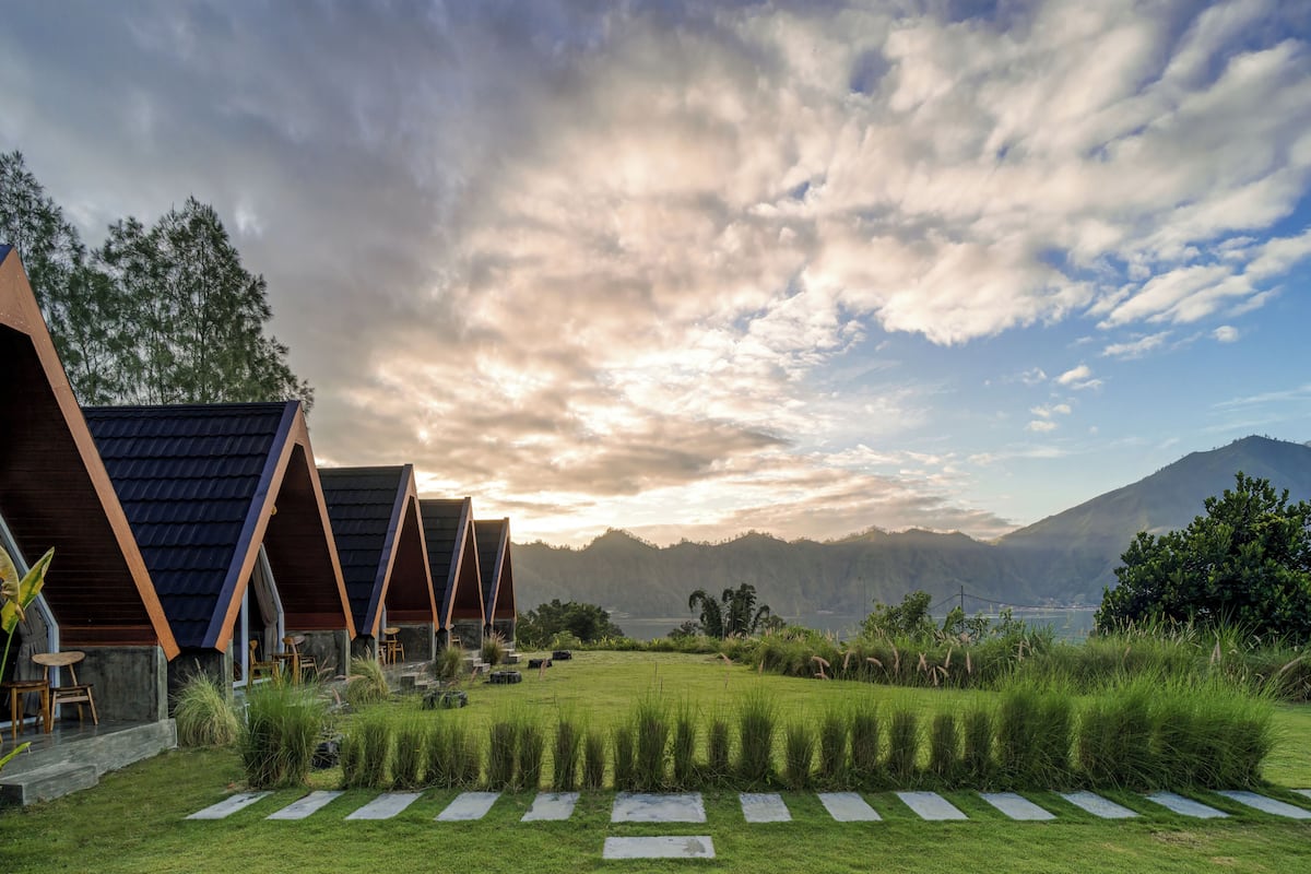 A row of modern, triangular-roofed buildings with a grassy lawn and stone pathways in front.