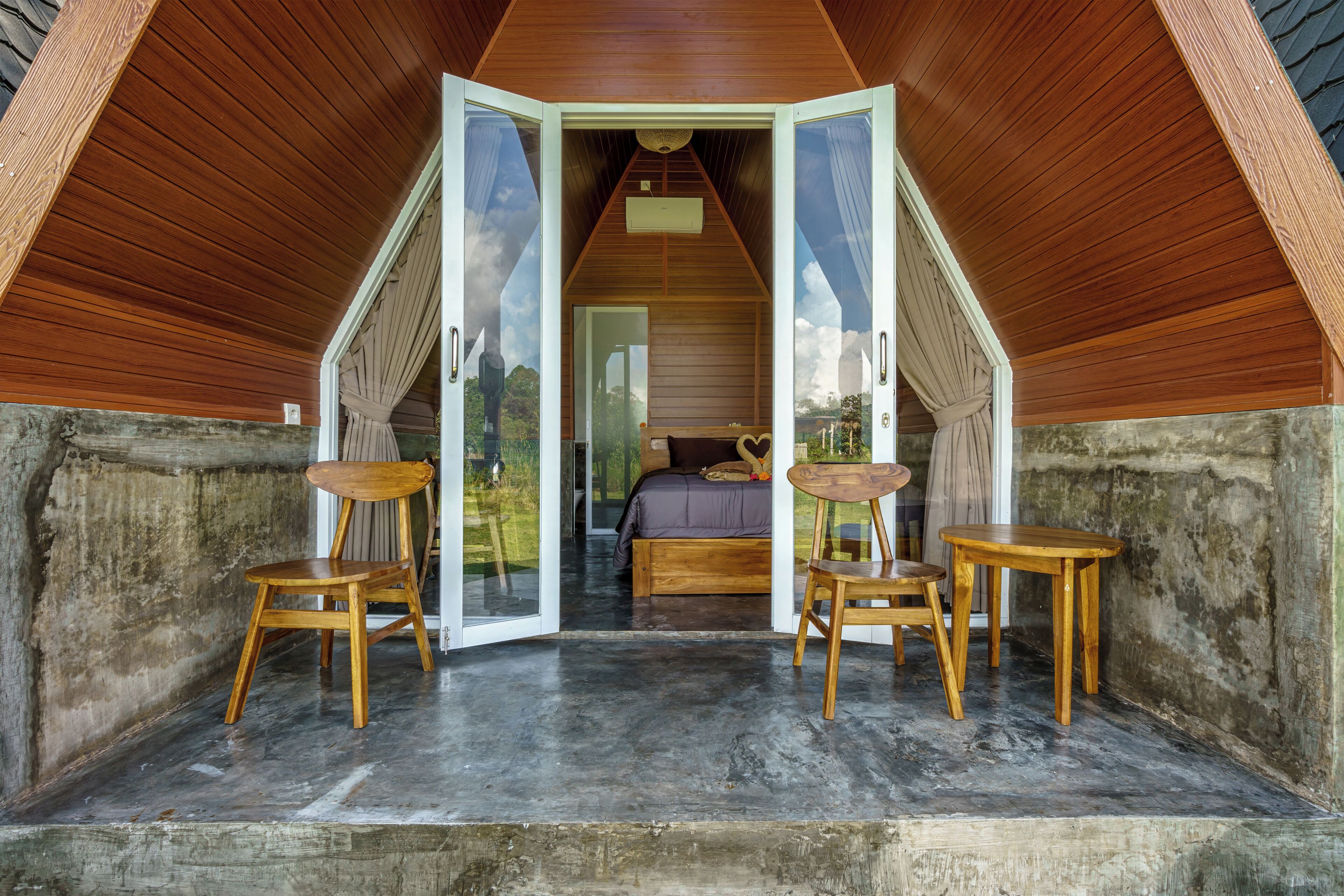 An attic bedroom with a sloped ceiling, wooden furniture, and a view of the landscape.