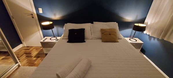 Relax in a spacious room with a large bed, two nightstands, and a lamp on each.