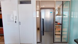 A compact kitchen with a built-in refrigerator, a microwave, and a small countertop. - COBAR0110 - Edifício Beta (Salvador)