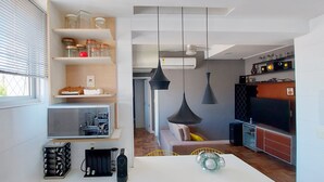 A modern kitchen with built-in shelves, a dining area, and a TV. - COBAR0110 - Edifício Beta (Salvador)