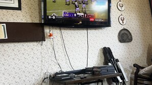 A living room with a television mounted on the wall, a wooden coffee table, and a gaming console. - 110 year old Renovated farm house in the heart of Cawcker city (Cawker City)