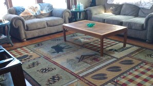 A living room with two sofas, a wooden coffee table, and a patterned rug. - 110 year old Renovated farm house in the heart of Cawcker city (Cawker City)
