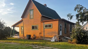 A two-story wooden house with a sloped roof and a covered porch. - 110 year old Renovated farm house in the heart of Cawcker city (Cawker City)