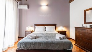 Une chambre à coucher avec un lit, des lampes de chevet, une commode, un climatiseur fixé au mur et une citation inspirante sur le mur.