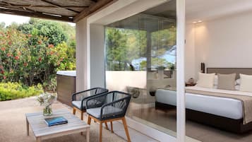 A modern bedroom with a glass door leading to a garden, a sofa, and a small table with a book.