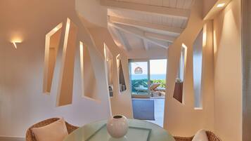 Un interior moderno con una mesa de vidrio, sillas de mimbre y vistas al exterior.