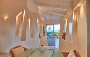 Ein modernes Interieur mit einem Glastisch, Korbstühlen und Blick ins Freie.