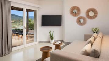 A modern living room with a sofa, a flat-screen TV, and a view of a patio with outdoor furniture.