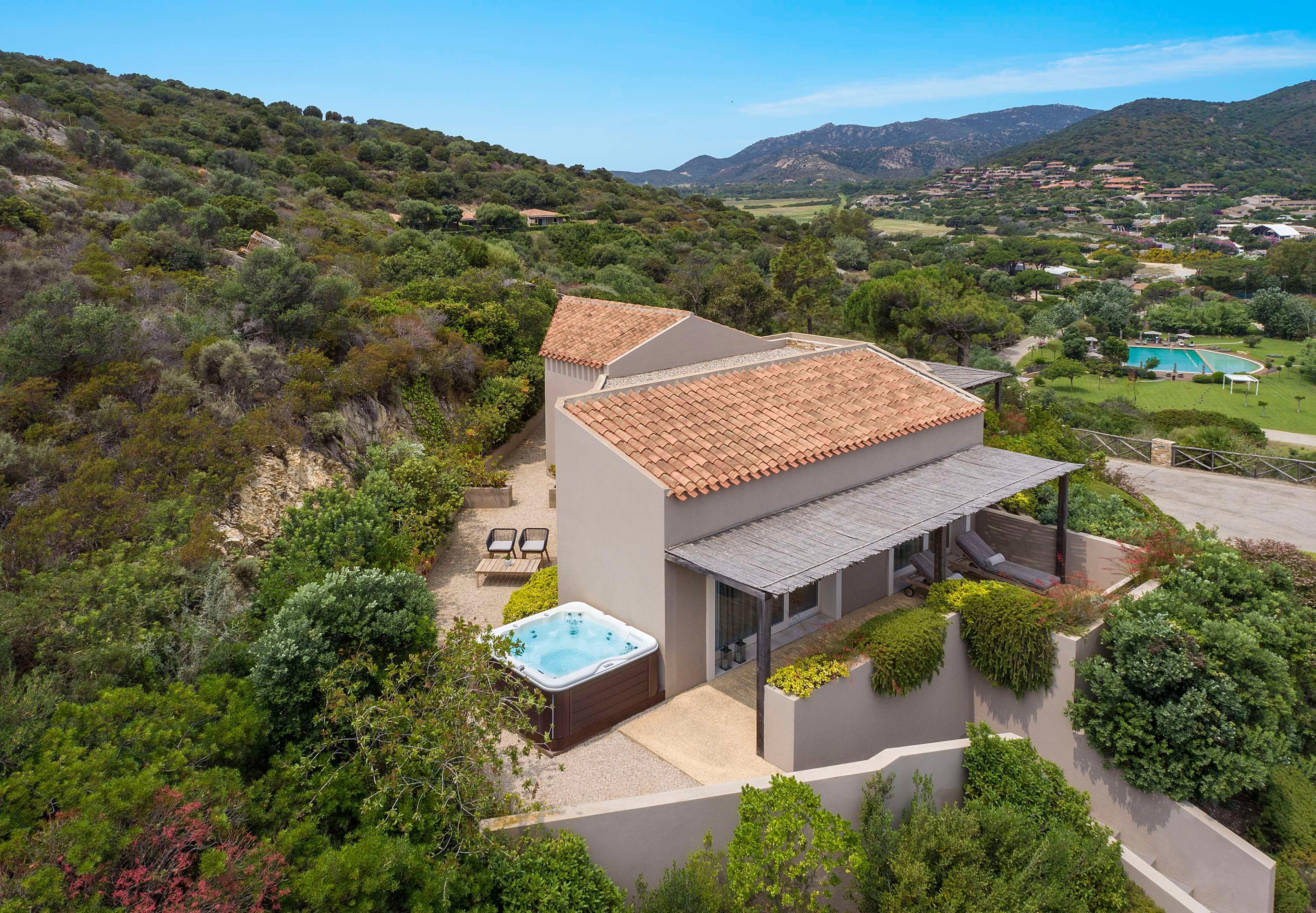Una casa moderna con techo de tejas, jacuzzi y vistas de las colinas circundantes.