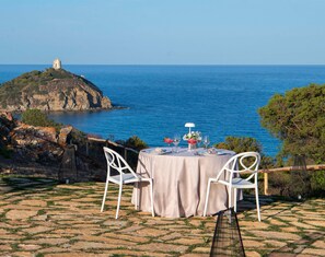 A table set for two with a view of the sea and a castle in the background. - Baia di Chia Resort Sardinia, Curio Collection (Domus de Maria)