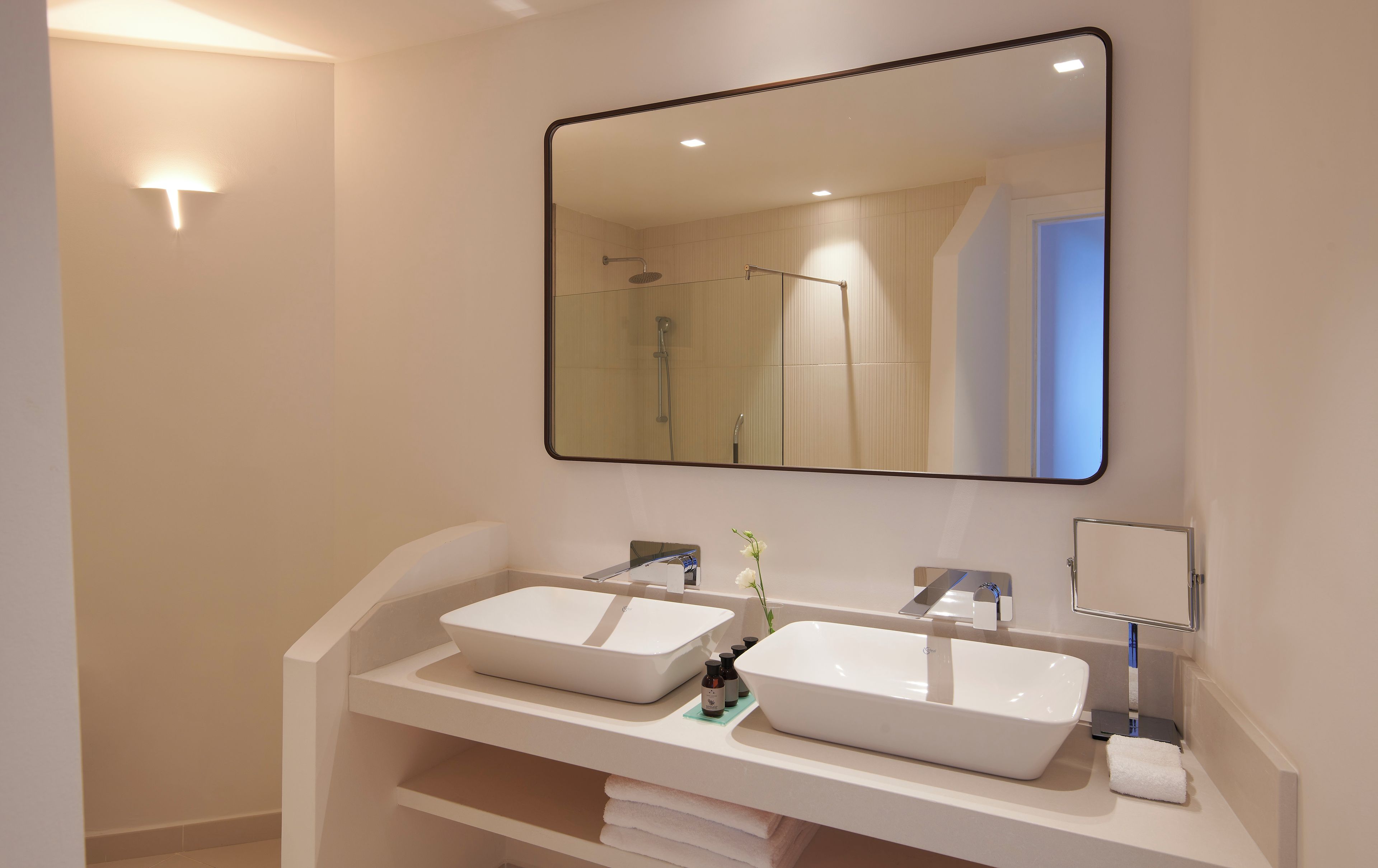 Ein modernes Badezimmer mit zwei Waschbecken, einem großen Spiegel und einer Dusche.