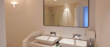 A modern bathroom with two vessel sinks, a large mirror, and a shower.